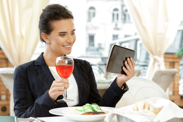 She is always working. Candid image of a beautiful smiling businesswoman using digital tablet in the cafe