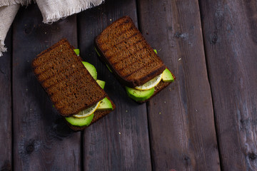 sandwiches with avocado on a wooden dark background