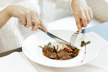 Healthy is delicious. Close up shot of a woman eating meat dish in a restaurant for lunch