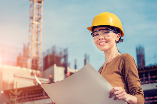 A Beautiful Young Asian Woman Civil Engineer Or Architect Is Reviewing Engineering Plans In Front Of A Construction Site