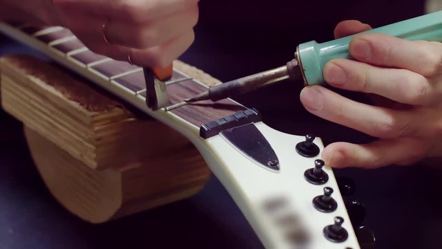Guitarist take old frets out with soldering iron 