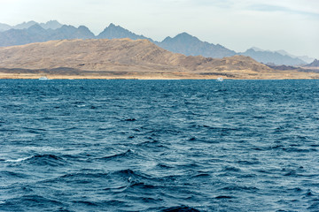 Seascape, view of the blue sea with high bald mountains in the background