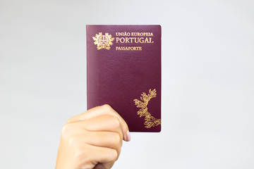 Hand holding  portuguese passport (Translation "European Union Portugal passport") white background.