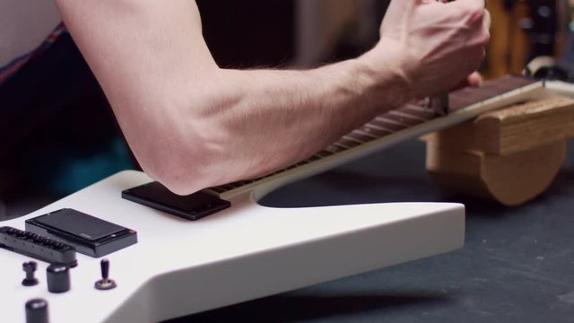 Man repairs guitar with soldering iron