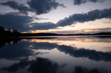 Calm lake in sweden at sunset with clouds reflecting in the water