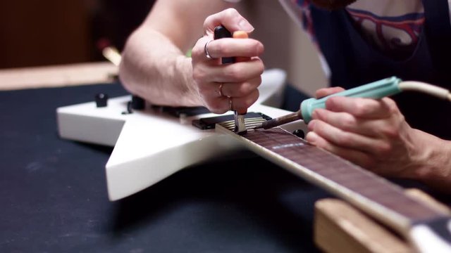 Artisan repairs guitar neck frets and fretboard