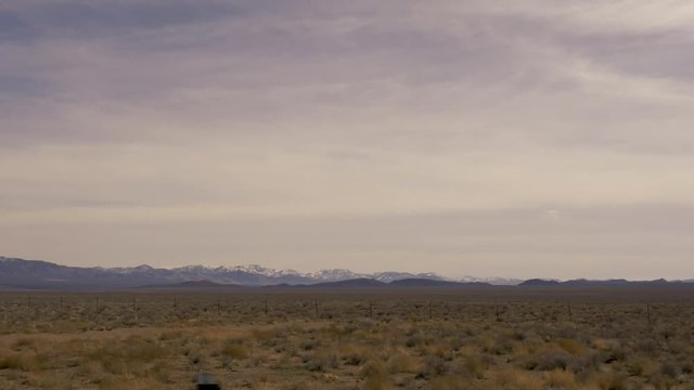 Passing low desert vegetation Nevada Great Basin Highway, US Highway 93 mountains in far distance-Drive Plate-POV