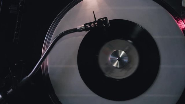 DJ turntable with a small seven-inch record is spinning. Bar party