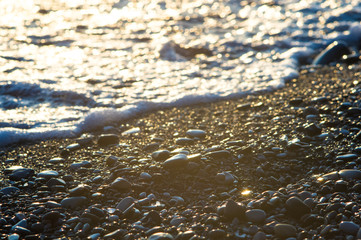pebble stones on the sea beach, the rolling waves of the sea with foam