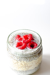 Oat pudding jar and chia seeds with raspberries on white background