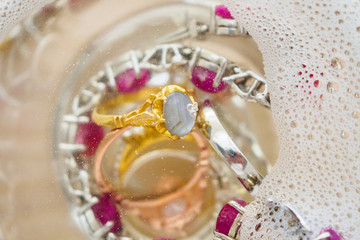 cleaning vintage jewelry diamond ring and bracelet in glass on wood table background