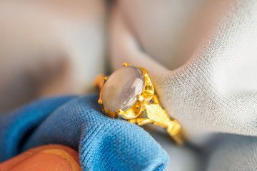 Jeweller hand polishing and cleaning gold jewelry ring with micro fiber fabric