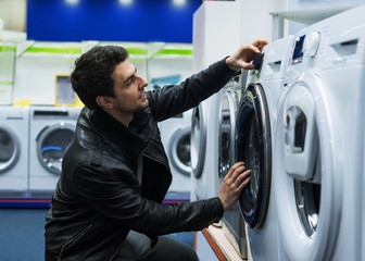portrait of male customer choosing washing machine in supermarket store