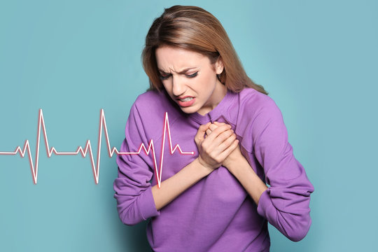 Young woman having heart attack on color background