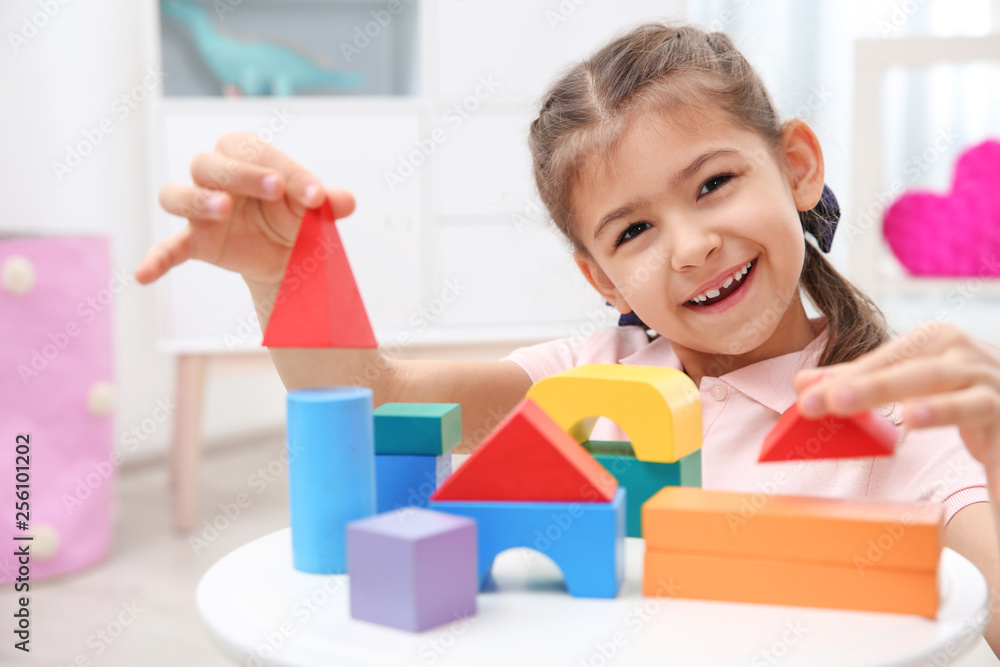 Poster Cute child playing with colorful blocks at home