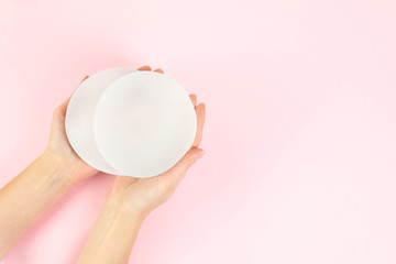 Woman holding silicone implants for breast augmentation on color background, top view with space...