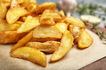 Delicious baked potato wedges on parchment paper, closeup - obrazy, fototapety, plakaty