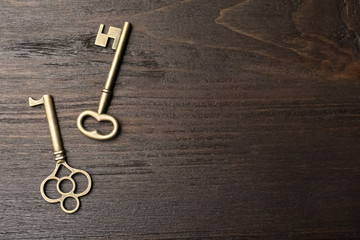 Old vintage keys on wooden background, flat lay. Space for text