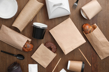 Flat lay composition with paper bags and different takeaway items on wooden background. Space for...