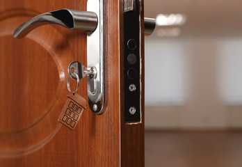Obraz premium Key with house-shaped trinket in door lock, closeup view