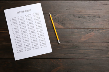 Answer sheet and pencil on wooden background, top view with space for text