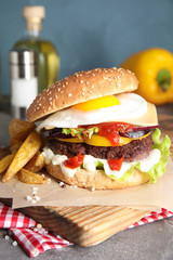 Tasty burger with fried egg on wooden board
