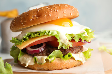 Tasty burger with fried egg on wooden board
