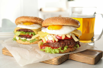 Tasty burgers with fried egg on wooden board