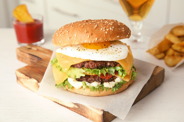 Tasty burger with fried egg on wooden board