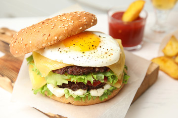 Tasty burger with fried egg on wooden board