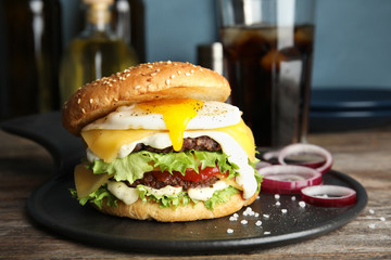 Tasty burger with fried egg on tray against blurred background