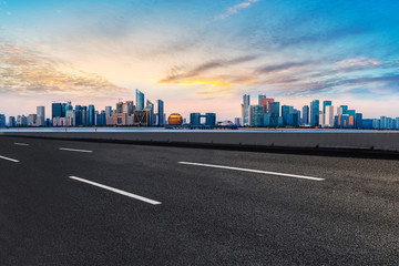 Fototapeta premium Foreground highway asphalt pavement city building commercial building office building