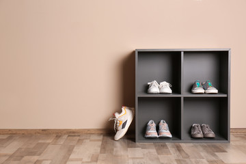 Modern cabinets with different sneakers near color wall, space for text