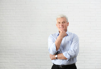 Portrait of handsome mature man near brick wall. Space for text