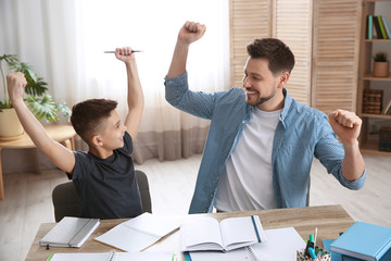 Happy dad and son after finishing homework in room