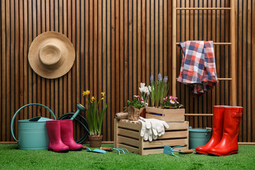 Fototapeta na wymiar Composition with different gardening tools on artificial grass at wooden wall. Space for text
