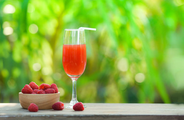 Summer juice glass raspberry cocktail and fresh raspberries fruit on wooden bowl