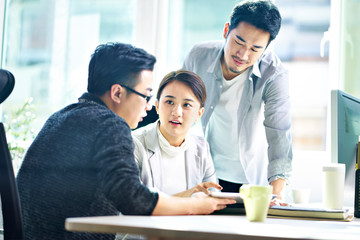 three asian corporate executives meeting in office