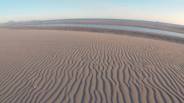 Parallel lines in the sand weaving their way to the pacific ocean. Video moving over the design on the beach.