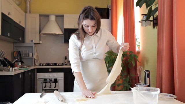 Happy woman tearing raw dough in the kitchen. The concept of a healthy diet and diet