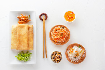 Traditional snacks of Chinese cuisine Dim Sum - tortillas - bings in a plate on a white background, spicy salads, vegetables, noodles. View from above.
