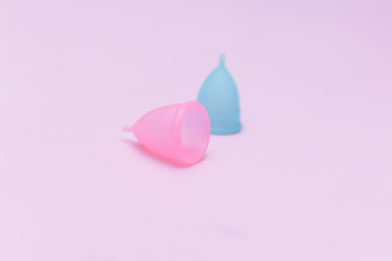 Two pink and blue period menstrual cup on a pink background. Concept of women's health, hygienic means of protection, menstruation, ecology of the planet.