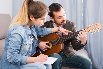 guitar tutor explaining basics to his female client at home