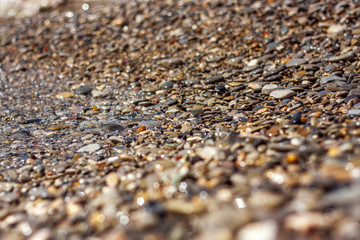 Sea pebble - beautiful gravel beach in sunlight, blurred background