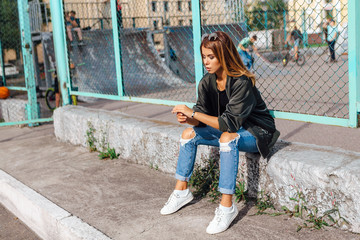 Fashion portrait of trendy young woman wearing sunglasses, and bomber jacket sitting next to rabitz...