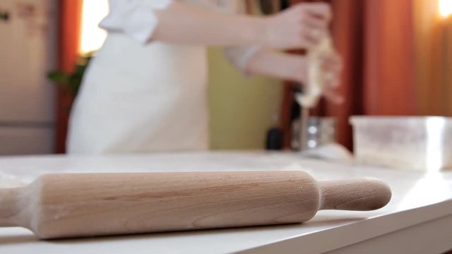 The girl in the apron puts the remains of raw dough in a plastic container