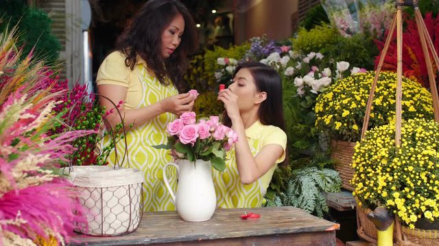 Lockdown of senior Asian woman teaching young Asian woman how to make flowers bunch