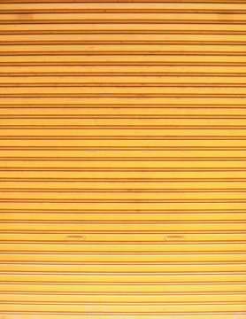 old detailed aged vintage yellow textured zinc alloy metal roller shutter door, store front exterior design used in construction industry as building material. Good for background, backdrop, wallpaper