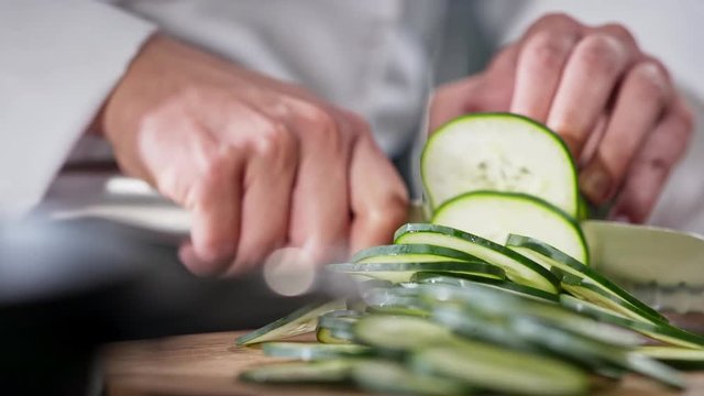 Chef slicing cucumber while slices pile up