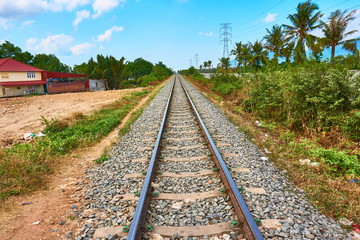Obraz premium railroad train tracks goes to horizon with palm trees